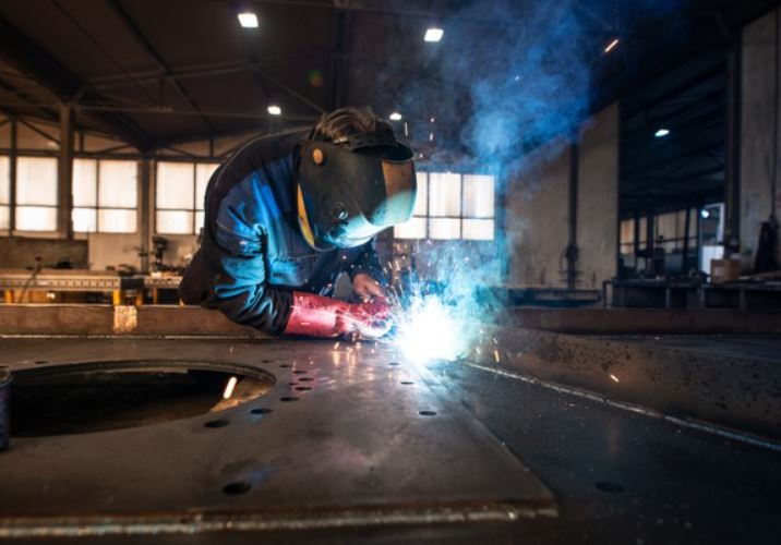 man cutting steel with protective gear and tools